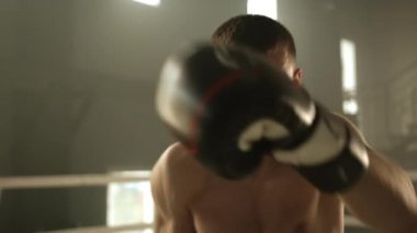 Kameraya bakarak gölge boksu yapan genç bir boksör. Sporcu, kameraya yumruk atar gibi havaya yumruk atıyor. Yüksek kalite 4k görüntü