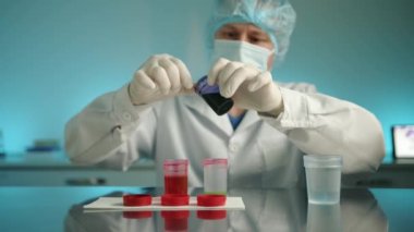Orta yaşlı erkek doktor, veteriner kliniğindeki laboratuvarda analiz yapılan konteynırlardan örnekler alıyor. Adam steril ortamda laboratuvar araştırması yapıyor. Yüksek kalite 4k görüntü
