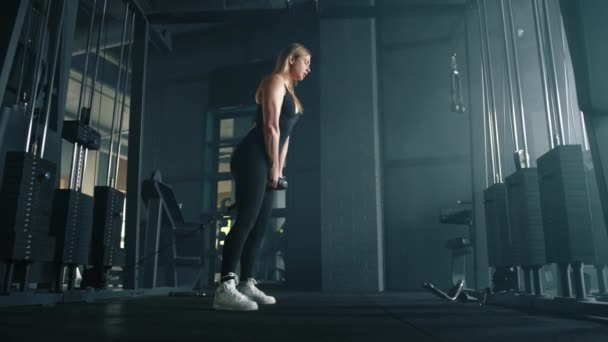 拍摄完整的漂亮的适合的金发女郎表演电缆拉通过锻炼在健身房 女人把绳子夹在两腿之间 然后翻过来 内饰是黑色的 高质量的4K镜头 — 图库视频影像
