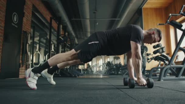 年轻健康的男人在健身房用哑铃做俯卧撑练习 处于推举位置的运动员将肘部抬高 使哑铃靠近胸板 高质量的4K镜头 — 图库视频影像