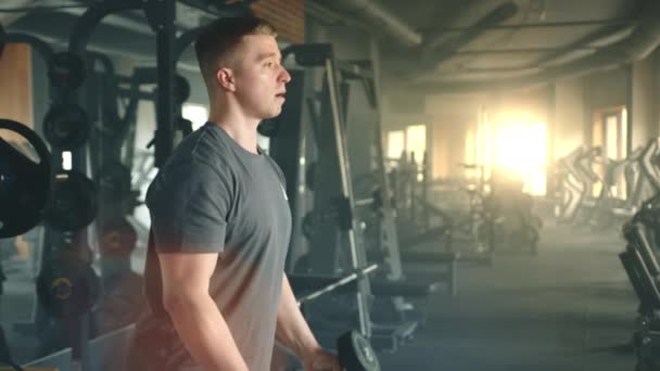 強度トレーニング機器とジムに立ってカールを実行するハンサムなスポーツマンの中ショット 人は訓練に集中している 腕のトレーニング 高品質4K映像 — ストック動画
