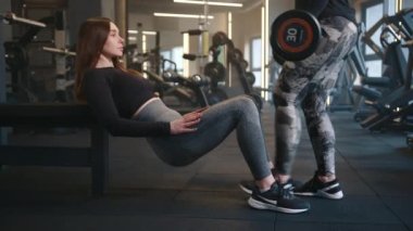 Formda bir kadın halter sallaması için başka bir atletik kadına halter veriyor. Bir kadın egzersiz yaparken, diğeri spor salonunda antrenman yapıyor. Yüksek kalite 4k görüntü