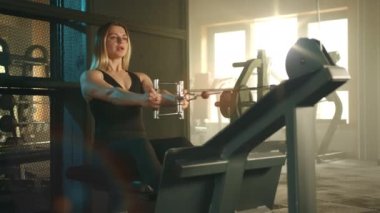 Siyah spor giysili güzel sarışın kablolu yayında kablo yayını yapıyor. Günışığıyla aydınlatılan modern tam donanımlı spor salonunda kadın egzersizleri. Yüksek kalite 4k görüntü