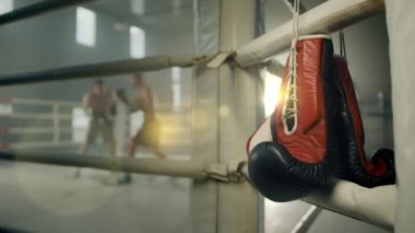 Bulanık boks maçı. İki boksör ringde birbirine yumruk atıyor. Bir çift kırmızı boks eldiveni beyaz renkli boks ringinde asılı duruyor. Yüksek kalite 4k görüntü