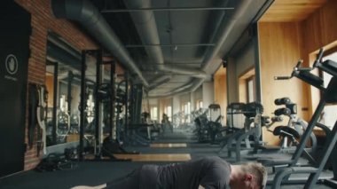 Tam teçhizatlı spor salonunda genç sporcu egzersizleri, şınav çekmeler. Dayanıklı eğitim ekipmanları, büyük ayna, arka planda siyah zemin. Yüksek kalite 4k görüntü