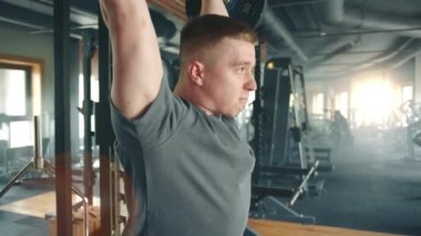 Spor salonunda halterli omuz presi yapan genç bir sporcunun orta boy fotoğrafı. Adam halteri omuzlarının önünde tutuyor ve halteri başının üstüne bastırıyor. Yüksek kalite 4k görüntü