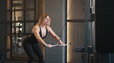 Siyah dar spor kıyafetleri içinde, kablo çapraz makinesinde tatlı sarışın. Kadın kablolu yayın yapıyor. Omuzlar, silah egzersizi. Yüksek kalite 4k görüntü