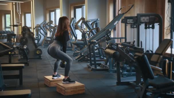 Wanita Atletik Melakukan Squat Dengan Kettlebell Berdiri Balok Kayu Kaki — Stok Video