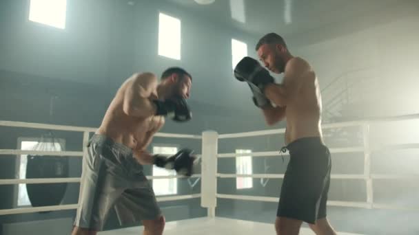 两名拳击手 年轻的和中年的 赤身裸体 戴着拳击手套 在体育馆里拳打脚踢 拳击手用正确的投掷拳对对手进行训练 高质量的4K镜头 — 图库视频影像
