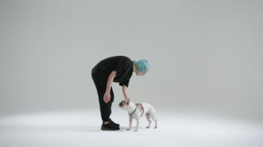 Dişi köpek eğitmeni evcil hayvan ve evet işareti yaptığı için Fransız bulldog 'unu tedavi ediyor. Kadın komutu doğru yerine getirene ödül olarak yemek veriyor. Yüksek kalite 4k görüntü