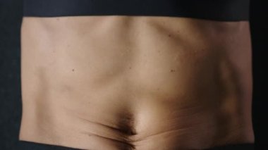 Siyah spor giyimli genç bir kadın siyah bir katta karın kaslarını çalıştırıyor, yakın plan. Ağır çekim. Üst Manzara. Yüksek kalite 4k görüntü