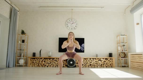 全镜头性感的金发舞女跳着蹲表演 在家锻炼 跳的时候 解开的金发跳了起来 背景中的现代内饰 高质量的4K镜头 — 图库视频影像