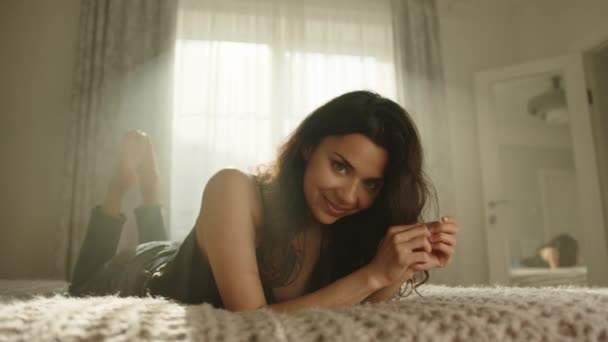 Привлекательная Юная Брюнетка Шелковой Ночнушке Позирует Перед Камерой Лежащей Животе — стоковое видео