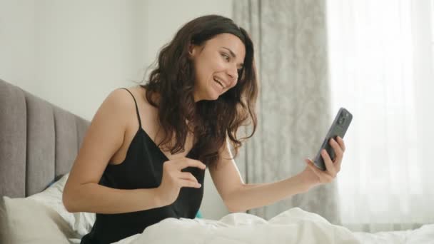 Gecelikli Beyaz Çarşaflı Dağınık Bir Yatakta Oturan Cep Telefonuyla Video — Stok video