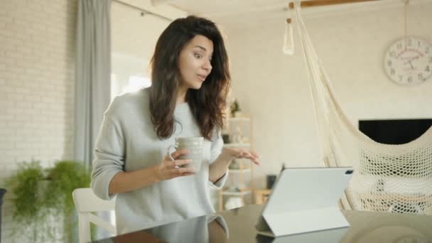 Çekici Esmer Tablette Oturup Çay Içerek Video Bağlantısıyla Iletişim Kuruyor — Stok video