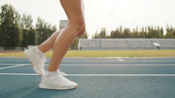 在体育场里 一名运动女子穿着白色袜子和运动鞋在田径运动跑道上奔跑 腿上汗流浃背 汗流浃背 足球场 背景音乐 高质量的4K镜头 — 图库视频影像