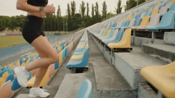 Kobieta Stonowana Spocone Ciało Biegnie Górę Stadionie Kolorowymi Fotelami Trening — Wideo stockowe