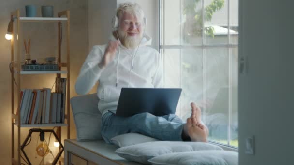 Homem Albino Barbudo Sorridente Relaxado Fones Ouvido Brancos Com Laptop — Vídeo de Stock