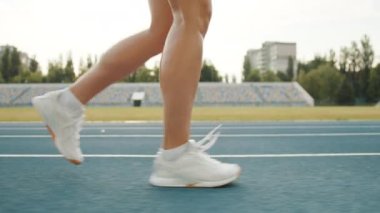 Beyaz çorapları ve spor ayakkabılarıyla terli kadın bacakları stadyumdaki atletizm pistinde koşuyor. Düz deniz dalgası renk rayları. Yüksek kalite 4k görüntü