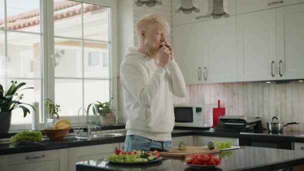 Genç Sakallı Albino Adam Akıllı Telefondan Konuşuyor Mutfakta Salatalık Yiyor — Stok video