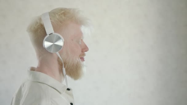 Jovem Homem Albino Feliz Com Olhos Fechados Fones Ouvido Brancos — Vídeo de Stock