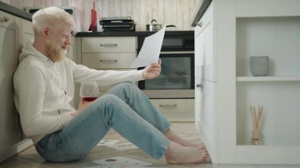 Slightly Drunk Albino Man Glass Red Wine Sitting Floor Kitchen — Stock Video