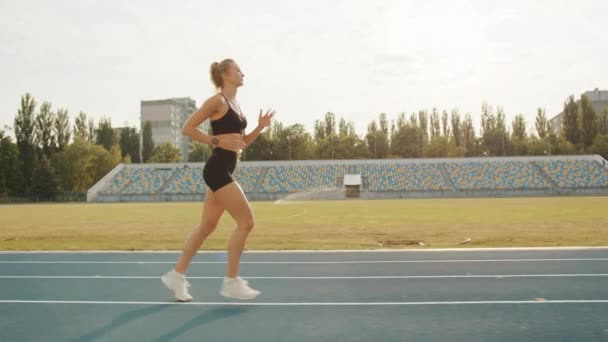 在体育场的田径运动跑道上 年轻迷人的金发姑娘被拍了一张相 穿着黑色紧身裤和上衣的年轻女子主要是跑步 高质量的4K镜头 — 图库视频影像