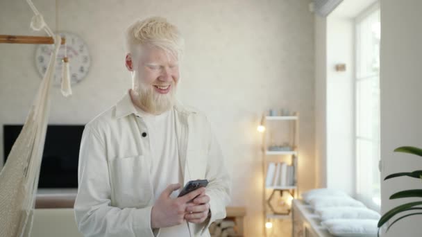 Glimlachende Jonge Albino Man Typen Chatten Smartphone Staan Lichte Woonkamer — Stockvideo