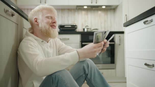 Joven Emocionado Con Albinismo Contando Dinero Sentado Suelo Cocina Casa — Vídeo de stock