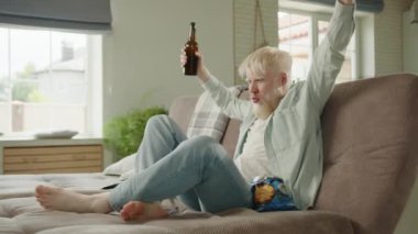 Albino adam futbol maçı izliyor, bira içiyor, cips yiyor, evdeki kanepede oturuyor. Albino erkeği en sevdiği takım için tezahürat yapar, kanepede dinlenir. Yüksek kalite 4k görüntü