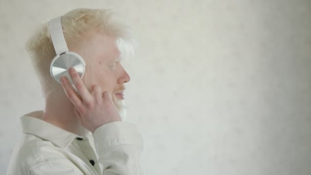 Фотография Молодого Альбиноса Закрытыми Глазами Белых Наушниках Слушающего Любимую Музыку — стоковое видео