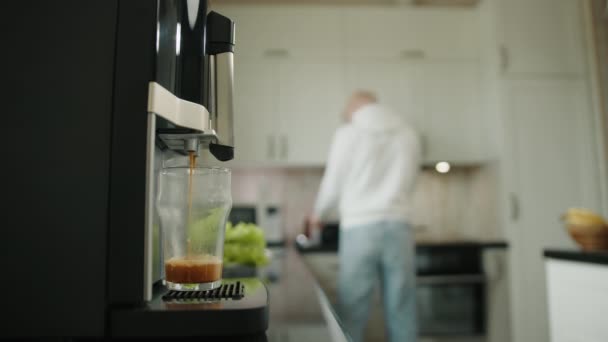コーヒーマシンでコーヒーを作るプロセス 白いキッチン家具のぼやけた背景 携帯電話で話しているアルビノの男のぼやけたシルエット 高品質4K映像 — ストック動画