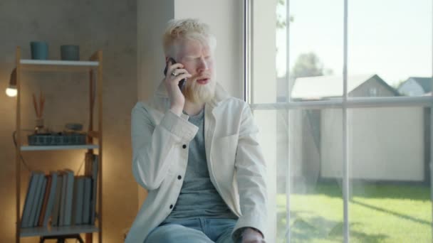 Serious Young Albino Man Having Conversation Smartphone Sitting Window Cozy — Stock Video