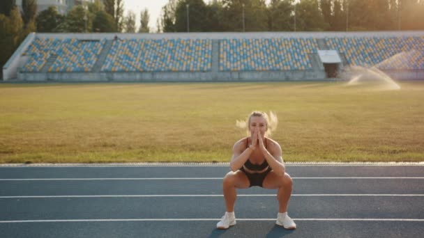 Sportif Sarışın Güneşli Bir Sabahta Stadyumdaki Koşu Pistinde Zıplayarak Çömelme — Stok video