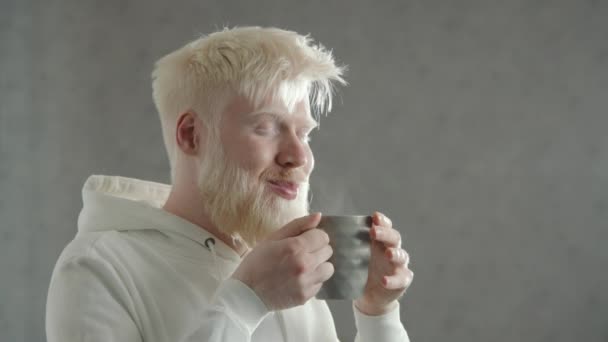Улыбающийся Альбинос Наслаждается Ароматом Горячего Напитка Серой Чашке Пробует Чрезвычайный — стоковое видео