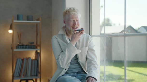Glad Ung Albino Man Talar Mobiltelefon Sitter Ett Rum Nära — Stockvideo