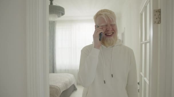 Joven Hombre Sonriente Con Albinismo Comunicándose Celular Caminando Casa Grande — Vídeo de stock
