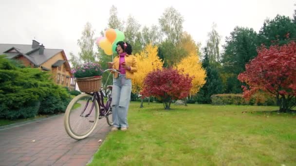 Glada Kvinna Hörlurar Flyttar Till Melodin Nära Cykel Med Ballonger — Stockvideo