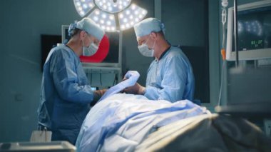 KYIV, UKRAINE - 6 Haziran 2023. Modern ameliyathanede ileri teknoloji ve teknikler kullanarak ameliyat yapan iki orta yaşlı plastik cerrah. Yüksek kalite 4k görüntü