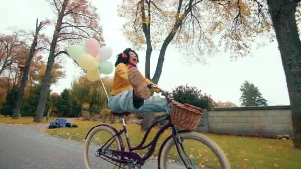 穿着女式自行车 头戴气球的辣妹沿着潮湿的小径缓缓地走向敞开的大门 一边听着耳机里的音乐 高质量的4K镜头 — 图库视频影像