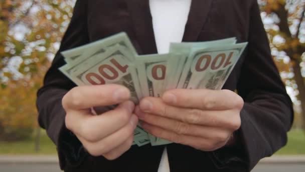 男性整洁的手的特写镜头 数着100美元的钞票 把现金放进黑色的夹克里 秋天公园的背景模糊不清 高质量的4K镜头 — 图库视频影像