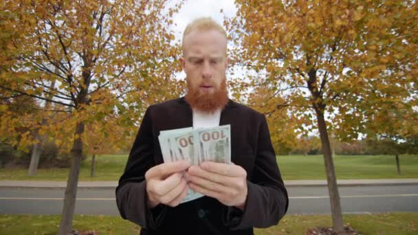 ひげを持つ若い赤毛の男は注意深くお金を集め 密かにブラックジャケットの内側のポケットに現金を入れました ゴールデンウィークの背景 高品質の4K映像 — ストック動画
