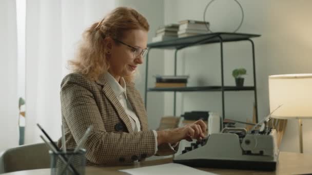 戴着眼镜 穿着白色T恤 穿着格子夹克 在老式打字机上打字 快乐迷人的女人 白天在舒适的现代公寓里吃饭 高质量的4K镜头 — 图库视频影像