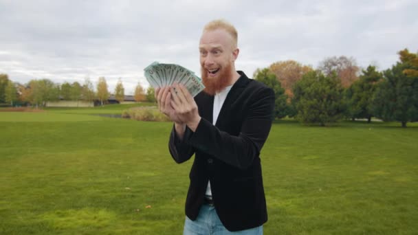 红头发的高个子男人兴高采烈地看着一堆钞票 回头看 笑得很开心 摇着头 摇着头 荒废的秋天公园高质量的4K镜头 — 图库视频影像