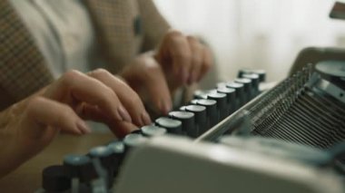 Kareli ceketli, beyaz tişörtlü, antika mekanik daktiloda çalışan, gündüzleri masada oturan güzel bakımlı bir kadın. Elle daktilo. Yüksek kalite 4k görüntü