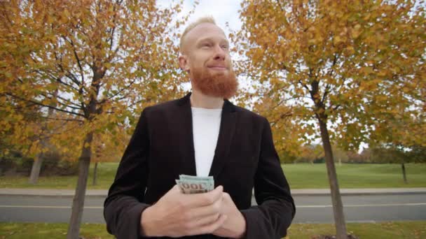 白いTシャツと黒いジャケットの男性は ドルを数え 内側のポケットに入れて周りを見回しました 背景にある美しい秋の木 高品質の4K映像 — ストック動画