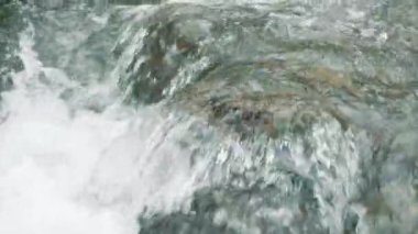 Çalkantılı köpüklü kristal berrak suların şelale gibi akması. Büyüleyici beyaz su çağlayanı hızla akıyor, dev taş blokları yıkıyor. Yüksek kalite 4k görüntü