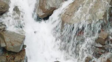 Durdurulamaz bir güçle akan su akıntısının sihirli görüntüsü, parlak kahverengi taşlara çarpıyor. Dağ deresi tarafından yıkılan taş bloklarla dolu bir yamaç. Yüksek kalite 4k görüntü