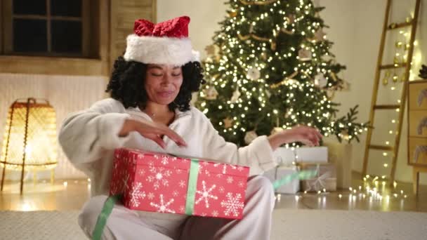 Щаслива Чорна Жінка Різдвяному Капелюсі Біла Піжама Сидять Підлозі Святковій — стокове відео