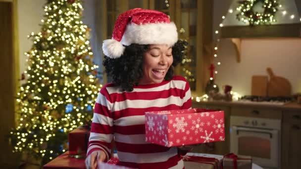 Улыбающаяся Молодая Афроамериканка Шляпе Санты Распаковывает Подарок Пожимает Плечами Приятным — стоковое видео